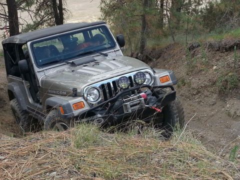 2005 Jeep Wrangler - A 2005 Jeep Wrangler Rubicon navigates a steep, wooded trail with its front wheels turned.