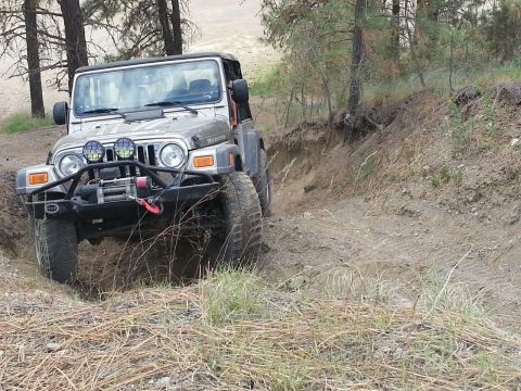 2005 Jeep Wrangler - A silver 2005 Jeep Wrangler navigates a challenging off-road trail, demonstrating its capabilities.