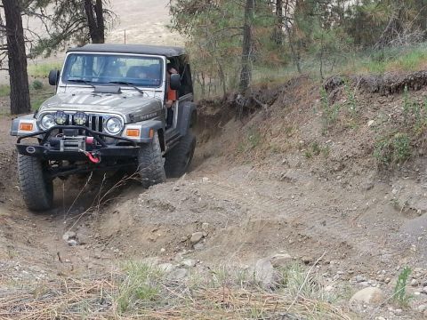 2005 Jeep Wrangler - Silver 2005 Jeep Wrangler Rubicon navigating a challenging dirt trail with trees in the background.