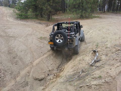 2005 Jeep Wrangler - Jeep Wrangler navigates a challenging off-road trail with steep inclines and loose dirt.