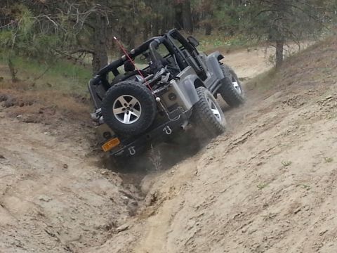 2005 Jeep Wrangler - A gray 2005 Jeep Wrangler tackles a challenging off-road trail, demonstrating its capability on rough terrain.