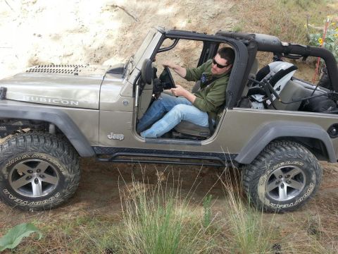 2005 Jeep Wrangler - A man drives a tan 2005 Jeep Wrangler Rubicon off-road.