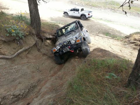 2005 Jeep Wrangler - A Jeep Wrangler navigates a challenging off-road trail, with another vehicle following in the background.