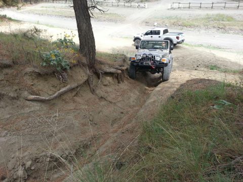 2005 Jeep Wrangler - A silver Jeep Wrangler navigates an off-road trail, followed by a white pickup truck.
