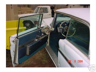 1960 Lincoln Premiere - The interior of a classic car is shown, with the driver's side door open, revealing blue upholstery and a steering wheel.
