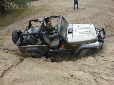 2005 Jeep Wrangler - A Jeep Wrangler navigates a challenging off-road terrain, getting stuck in a deep dirt rut.