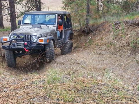 2005 Jeep Wrangler - A Jeep Wrangler navigates a challenging off-road trail, demonstrating its capability on uneven terrain.