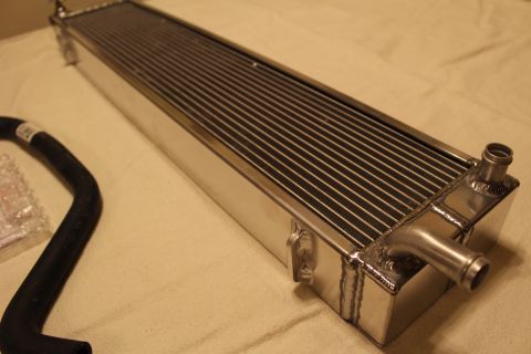 2003 Ford Crown Victoria - Close angled view of a polished aluminum heat exchanger showing a welded end tank and barbed hose fitting.