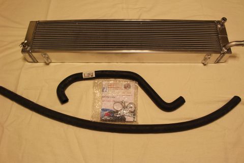 2003 Ford Crown Victoria - aluminum heat exchanger displayed above two black rubber hoses and a clear bag of clamps and hardware.