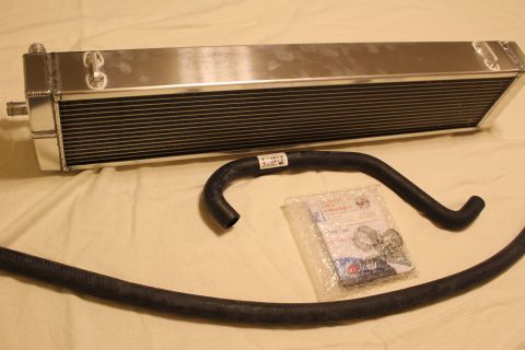 2003 Ford Crown Victoria - aluminum heat exchanger is displayed above a black coolant hose and a sealed bag of mounting hardware.