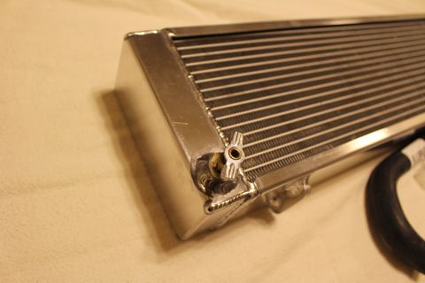 2003 Ford Crown Victoria - Macro close-up of an aluminum heat exchanger corner showing the fin core, weld beads and a small brass drain.