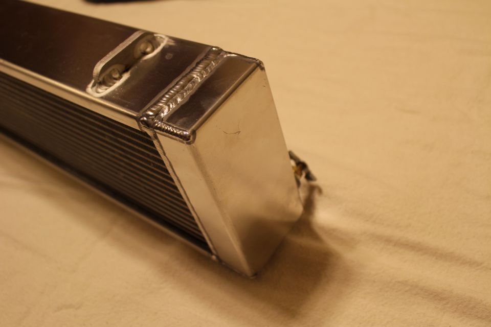 Close-up of welded end cap on a polished aluminum heat exchanger core