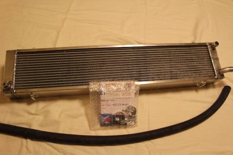 2003 Ford Crown Victoria - polished aluminum heat exchanger with a bubble-wrapped bag of hardware and a black rubber hose laid on a tan cloth.