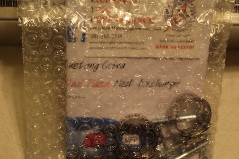 2003 Ford Crown Victoria - bubble-wrapped parts bag with a printed label reading Mustang Cobra Dual Pass Heat Exchanger and a vendor phone number.