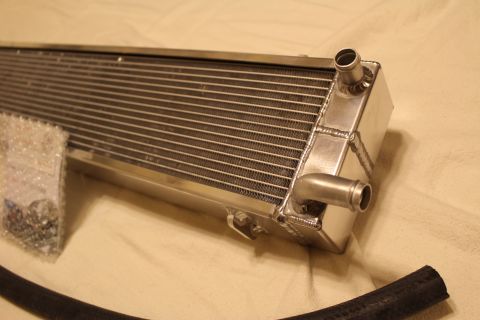 2003 Ford Crown Victoria - Angled close-up of a brushed aluminum heat exchanger end tank showing two hose barb fittings and welded seams.