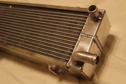2003 Ford Crown Victoria - Macro view of an aluminum heat exchanger end tank with two barb fittings, welded seams and the brazed core fins.