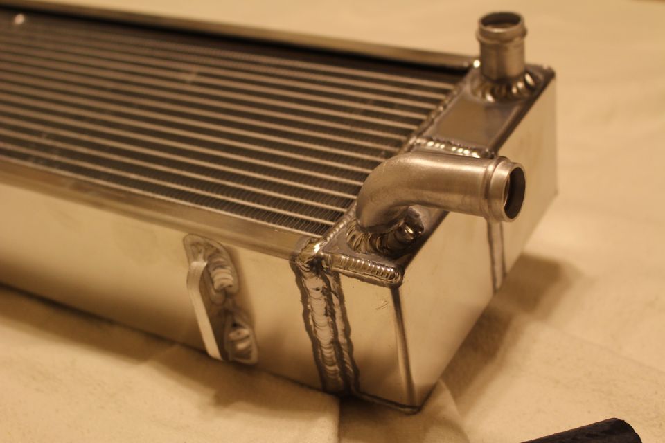 Close-up of aluminum heat exchanger end tank with two angled barb fittings