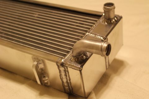 2003 Ford Crown Victoria - Close-up of an aluminum heat exchanger end tank with a vertical and an angled hose barb fitting and welded seams.