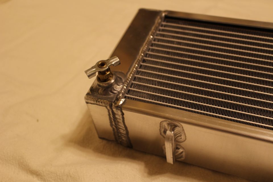 Close-up of aluminum heat exchanger corner with small brass petcock fitting