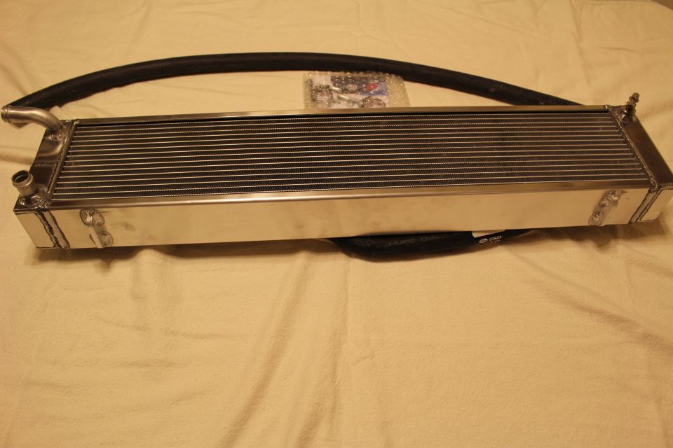 Polished aluminum heat exchanger with long curved black hose and hardware bag