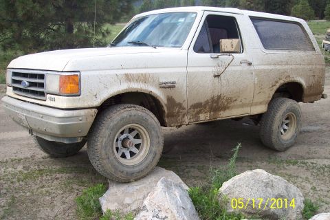 1990 Ford Bronco - This white Ford Bronco is covered in mud, indicating off-road use.