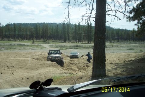1990 Ford Bronco - A Jeep Wrangler maneuvers through a challenging sandy terrain, with another vehicle following closely behind.