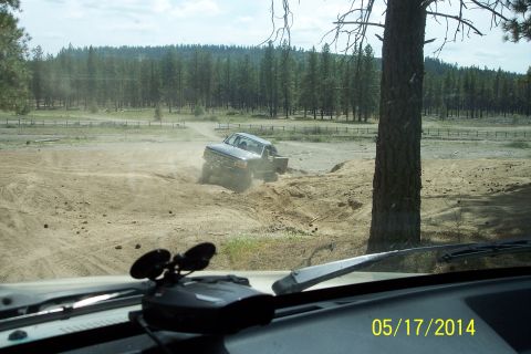 1990 Ford Bronco - A Ford truck navigates a challenging off-road course, kicking up a cloud of dust as it goes.