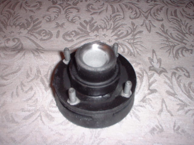 car strut mount with four bolts on a patterned cloth surface
