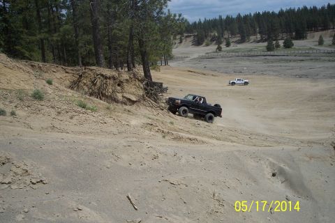 1990 Ford Bronco - A black 1990 Ford Bronco navigates a steep dirt incline with another vehicle visible in the distance.
