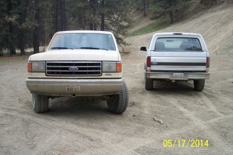 1990 Ford Bronco - Two Ford Broncos are parked on a dirt road in a wooded area. The front Bronco is a 1987 model.