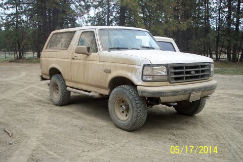 1990 Ford Bronco - This 1990 Ford Bronco is heavily coated in mud, suggesting recent off-road use.