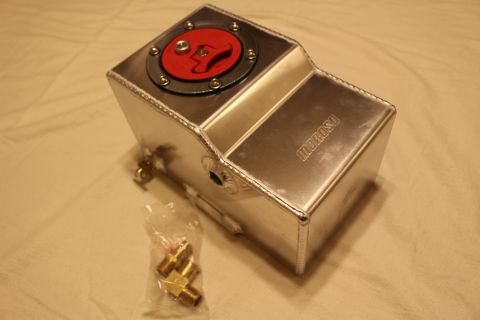 2003 Ford Crown Victoria - Angled view of a polished aluminum fluid reservoir tank with a red flush-mount filler cap and a bag of brass fittings.