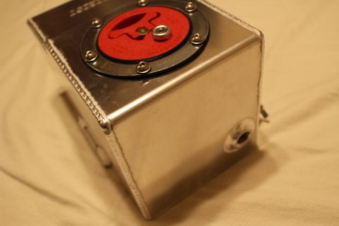 2003 Ford Crown Victoria - Corner view of a welded aluminum fuel cell highlighting its seam welds, red flip-up cap and a threaded side bung.