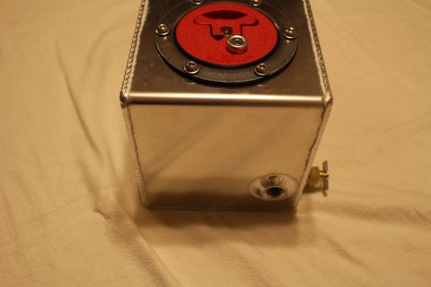 2003 Ford Crown Victoria - End view of a polished aluminum fuel cell with its red flip-up cap up top and a brass fitting threaded into a side bung.