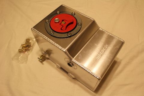 2003 Ford Crown Victoria - welded aluminum fuel cell bearing a Moroso logo, its red flip-up cap closed, with a bag of brass fittings alongside.