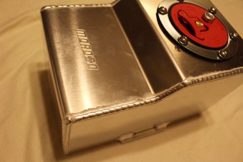 2003 Ford Crown Victoria - Low-angle view of a welded aluminum fuel cell, its TIG seam welds and embossed Moroso logo prominent, red cap at the corner.