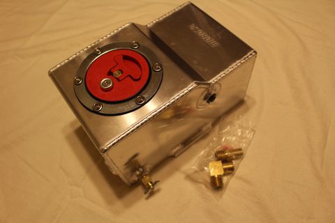 2003 Ford Crown Victoria - polished aluminum fuel cell with red flip-up cap and brass drain petcock, shown alongside a bag of brass AN fittings.