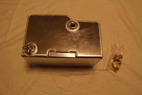 2003 Ford Crown Victoria - Underside view of a welded aluminum fuel cell with a recessed handle and threaded bungs, shown beside a bag of brass parts.