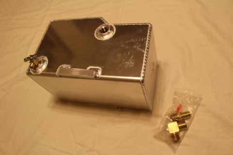2003 Ford Crown Victoria - Rear three-quarter view of a welded aluminum fuel cell with welded bungs and brass fittings, beside a bag of brass parts.