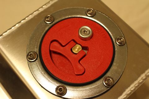 2003 Ford Crown Victoria - close-up shows the red flip-lever quick-fill fuel cap, ringed by six stainless bolts and mounted to a brushed aluminum tank.