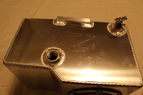 2003 Ford Crown Victoria - close-up of an aluminum fuel cell's welded top face shows a threaded bung, a brass petcock valve, and a recessed carry handle.