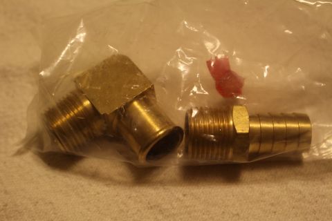 2003 Ford Crown Victoria - close-up of a brass elbow and threaded hose-barb fitting in a clear bag, with a small red zip tie alongside.