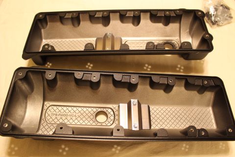 2003 Ford Crown Victoria - Two black plastic engine valve covers rest interior-side-up beside a small bag of mounting hardware.