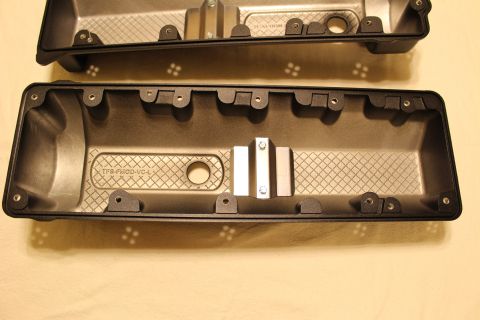 2003 Ford Crown Victoria - black plastic valve cover cast with 'TFS-FMOD-VC-L' is shown interior-side-up, with a polished metal clip across its center.