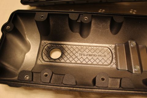 2003 Ford Crown Victoria - Close-up of the inside of a black valve cover showing a crosshatch baffle and cast lettering reading TFS-FMOD-VC-R.