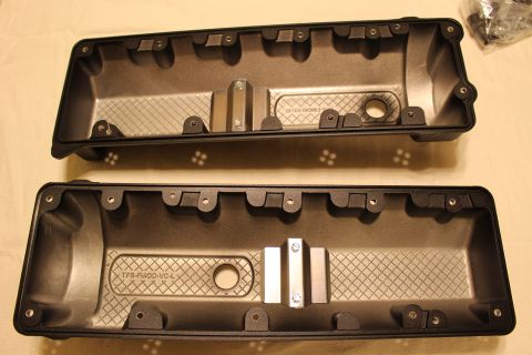 2003 Ford Crown Victoria - pair of black valve covers laid upside down on a tan cloth, their crosshatched baffled undersides facing the camera.