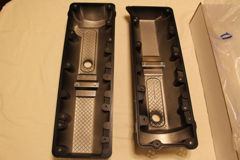 2003 Ford Crown Victoria - Two black valve covers arranged side by side on a cloth with their finned baffle undersides exposed, beside an open box.