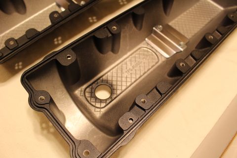 2003 Ford Crown Victoria - Close-up of a pair of cast aluminum modular V8 valve covers finished in textured satin black, sitting upside down on a light countertop wit…