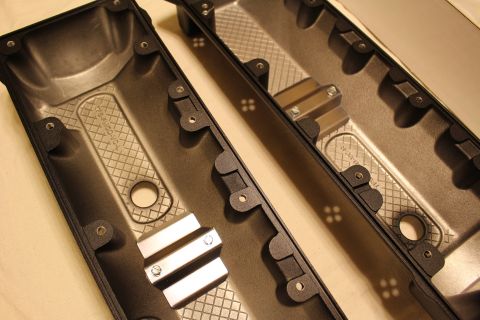 2003 Ford Crown Victoria - Angled close-up of two valve cover undersides with crosshatched baffle plates and machined aluminum mounting blocks.