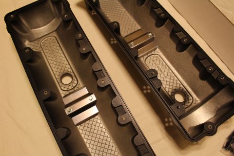 2003 Ford Crown Victoria - Two valve covers lying upside down on a cloth, each showing diamond-pattern internal baffling and aluminum spacer blocks.